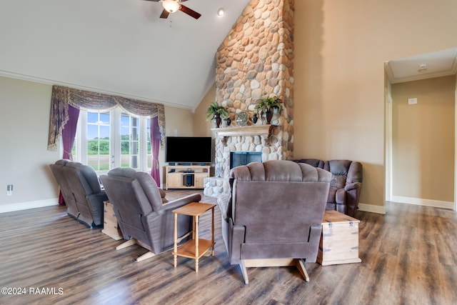 living room with crown molding, ceiling fan, high vaulted ceiling, dark hardwood / wood-style flooring, and a stone fireplace