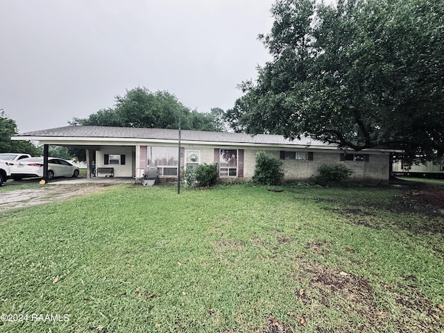 view of front facade with a front yard, an attached carport, and driveway