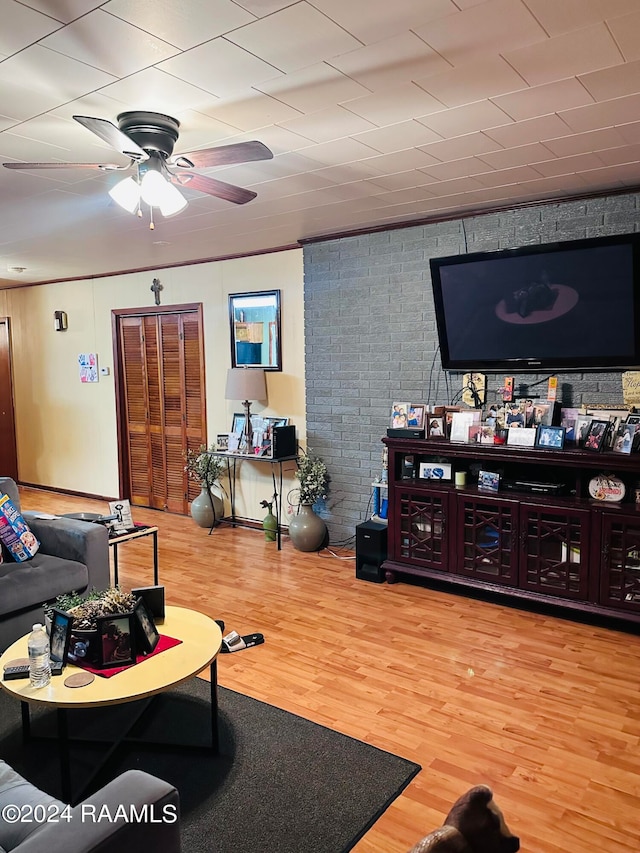 living room with ceiling fan, brick wall, and wood-type flooring