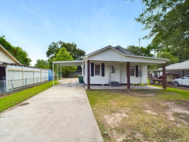 view of front of home featuring covered porch, a carport, and a front lawn