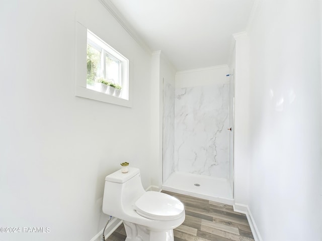 bathroom with toilet, a tile shower, crown molding, and hardwood / wood-style floors