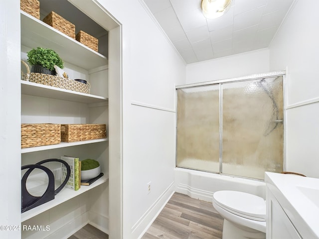 full bathroom featuring enclosed tub / shower combo, toilet, vanity, hardwood / wood-style floors, and ornamental molding