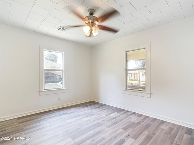 empty room with ceiling fan, wood finished floors, visible vents, and baseboards