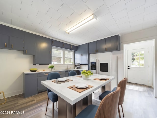 kitchen featuring hardwood / wood-style flooring, sink, a center island, fridge with ice dispenser, and a kitchen breakfast bar