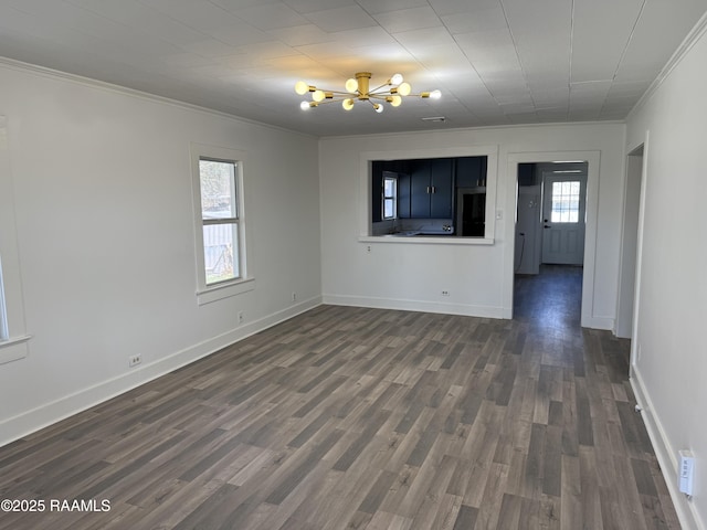 empty room featuring baseboards, dark wood-type flooring, a chandelier, and crown molding