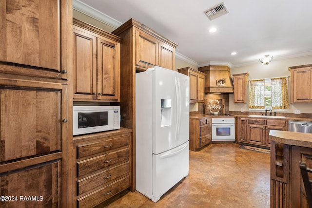 kitchen featuring white appliances, crown molding, sink, and premium range hood