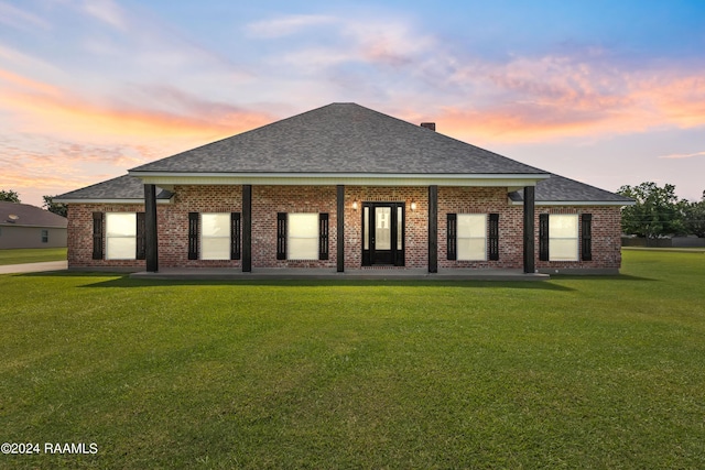 back house at dusk featuring a yard