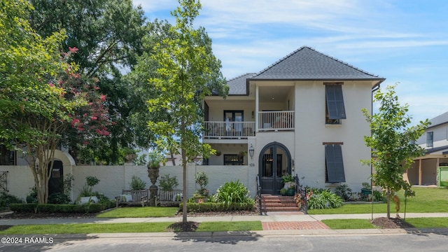 view of front of property with a balcony and a front lawn