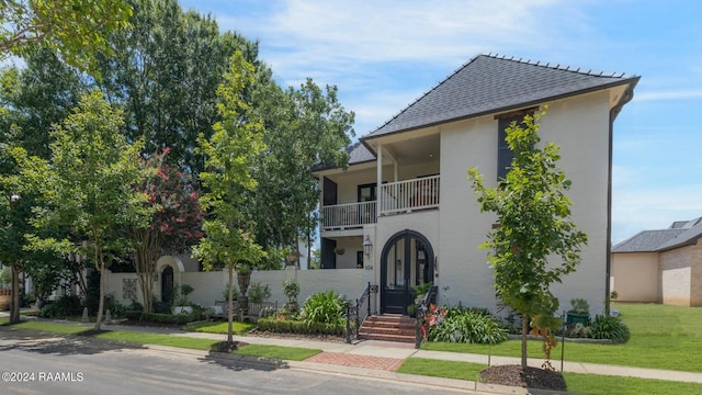 view of front of home featuring a balcony and a front lawn