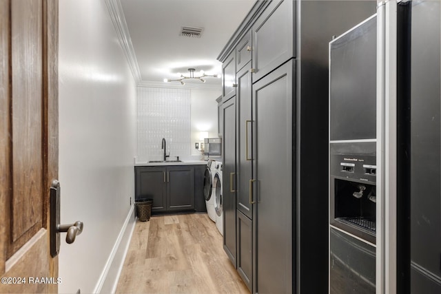 kitchen with sink, ornamental molding, stainless steel fridge, gray cabinets, and light wood-type flooring