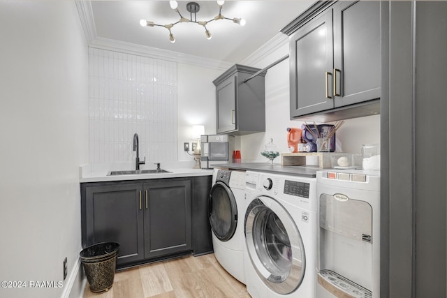 laundry area featuring cabinets, crown molding, sink, light wood-type flooring, and washing machine and clothes dryer