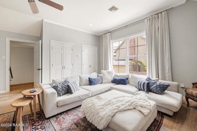 living room featuring ceiling fan, ornamental molding, and light wood-type flooring