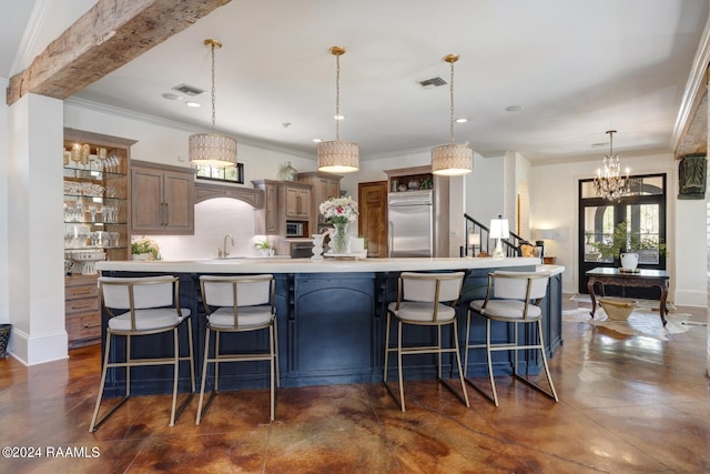 kitchen featuring sink, tasteful backsplash, built in refrigerator, pendant lighting, and a kitchen bar