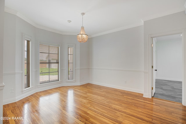 empty room with crown molding, a chandelier, and light hardwood / wood-style floors