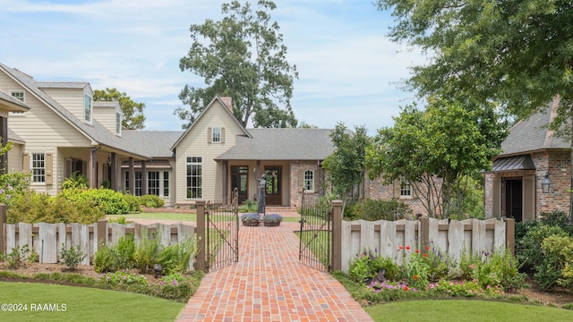 view of front of home with a fenced front yard, a gate, and brick siding