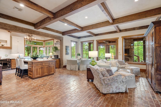 living area with visible vents, a notable chandelier, beam ceiling, and brick floor