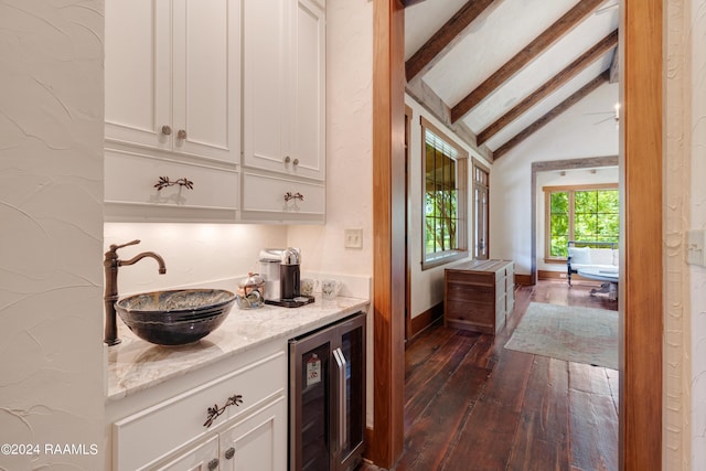 kitchen with white cabinetry, a sink, lofted ceiling with beams, and beverage cooler
