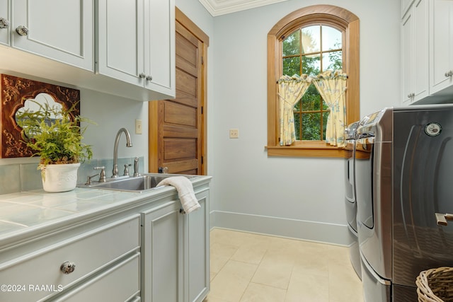 laundry room with cabinet space, a sink, independent washer and dryer, and crown molding