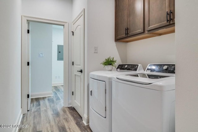 laundry area with independent washer and dryer, electric panel, cabinets, and light wood-type flooring