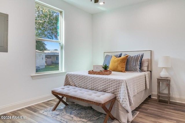 bedroom with electric panel and wood-type flooring