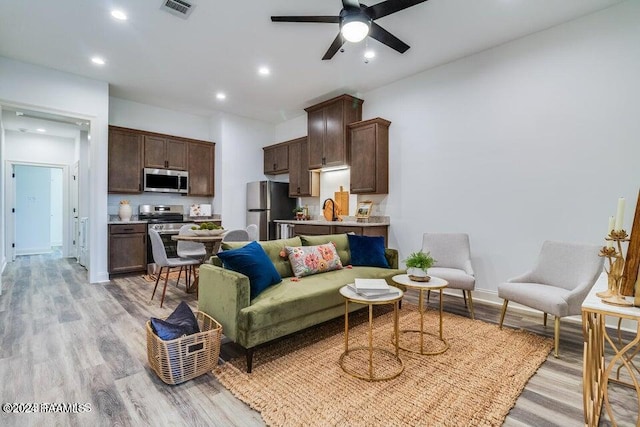 living room featuring ceiling fan, sink, and light hardwood / wood-style floors