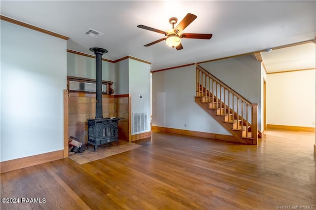 319 Goodwin St, Welsh, LA 70591 - unfurnished living room featuring ornamental molding, wood finished floors, ceiling fan, a wood stove, and stairs