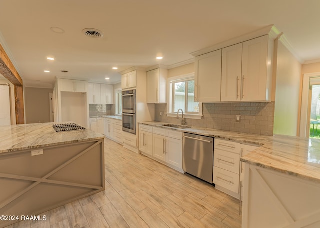 kitchen featuring sink, light stone counters, crown molding, appliances with stainless steel finishes, and white cabinets