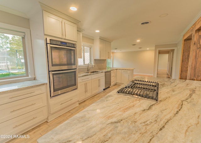 kitchen featuring stainless steel appliances, white cabinetry, light stone countertops, and sink