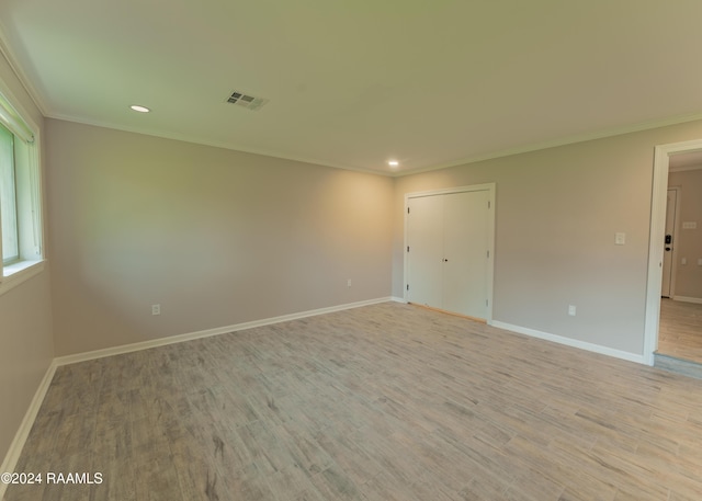 empty room with crown molding and light hardwood / wood-style flooring