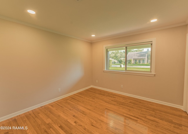 spare room with ornamental molding and light hardwood / wood-style flooring