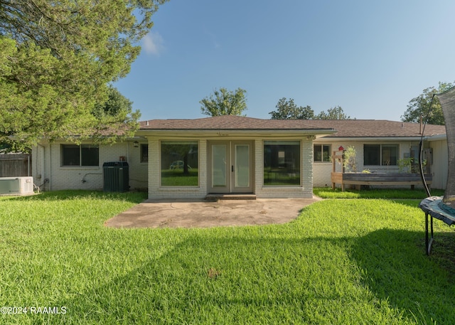 back of house featuring central AC, a trampoline, a patio, and a lawn