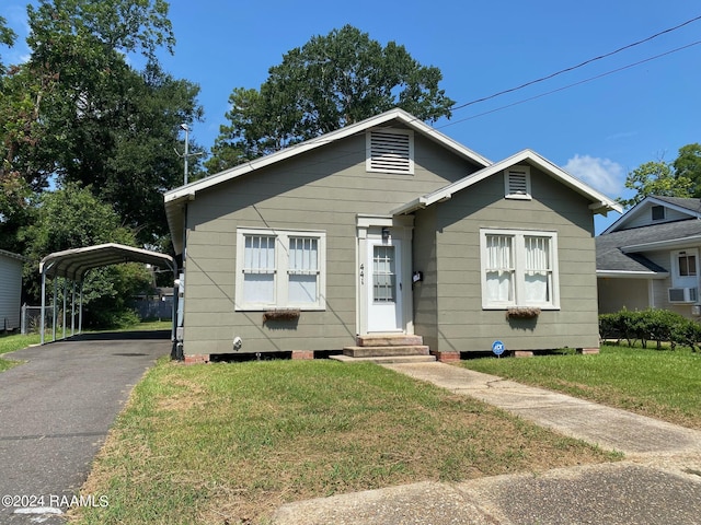 bungalow-style home with a carport and a front lawn