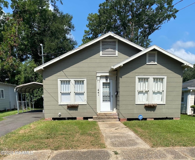 bungalow-style house featuring a carport and a front yard