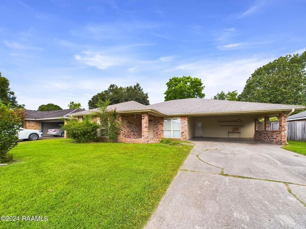 ranch-style house with an attached carport, a front lawn, concrete driveway, and brick siding