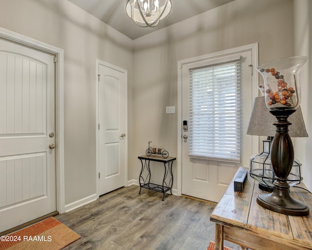 foyer entrance with a wealth of natural light, an inviting chandelier, and hardwood / wood-style flooring