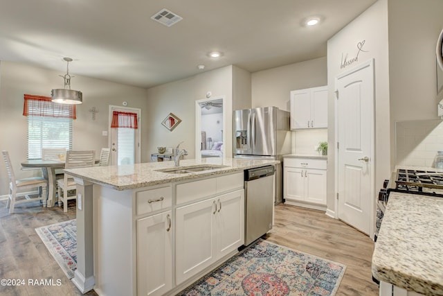 kitchen featuring a kitchen island with sink, sink, appliances with stainless steel finishes, tasteful backsplash, and white cabinetry