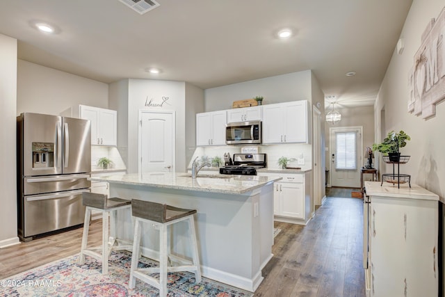 kitchen with white cabinetry, sink, light hardwood / wood-style flooring, an island with sink, and appliances with stainless steel finishes