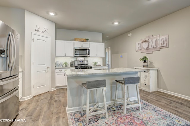 kitchen featuring appliances with stainless steel finishes, sink, white cabinetry, and an island with sink