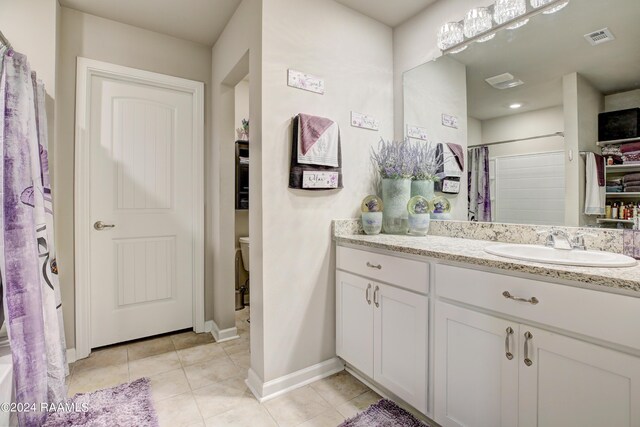 bathroom with toilet, vanity, tile patterned floors, and curtained shower