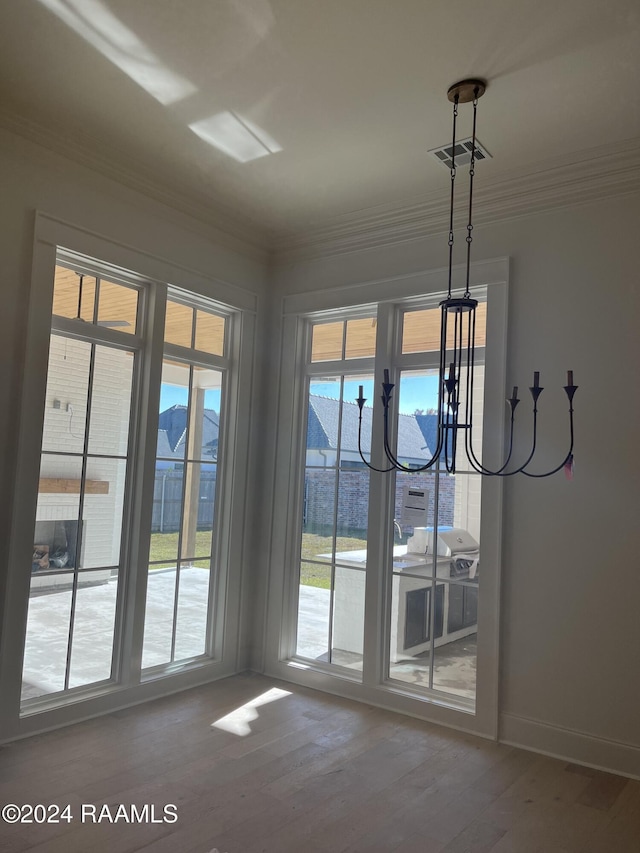 doorway to outside with a notable chandelier, hardwood / wood-style floors, and crown molding