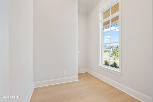 empty room featuring ornamental molding, light wood-style flooring, and baseboards