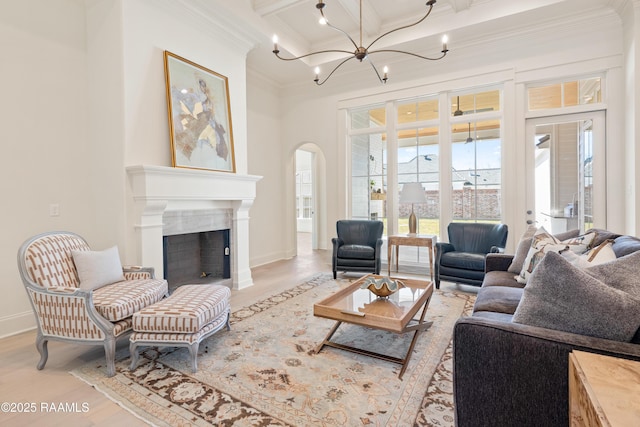 living area with light wood finished floors, arched walkways, coffered ceiling, ornamental molding, and beamed ceiling