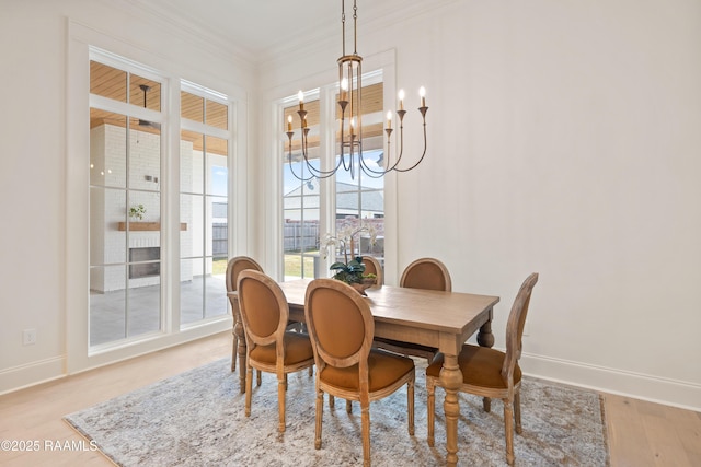 dining room featuring a chandelier, ornamental molding, baseboards, and light wood-style floors