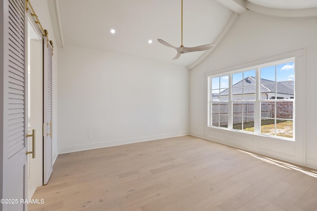 empty room featuring ceiling fan, vaulted ceiling with beams, a barn door, recessed lighting, and light wood finished floors