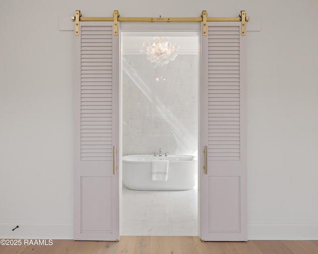 room details with a barn door, a freestanding tub, and baseboards