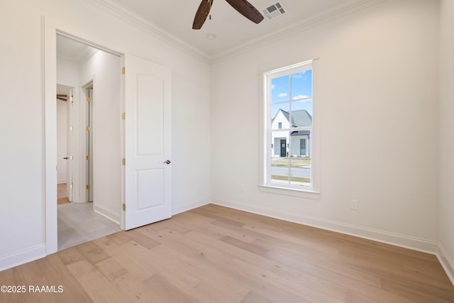 empty room with a ceiling fan, visible vents, baseboards, ornamental molding, and light wood-type flooring