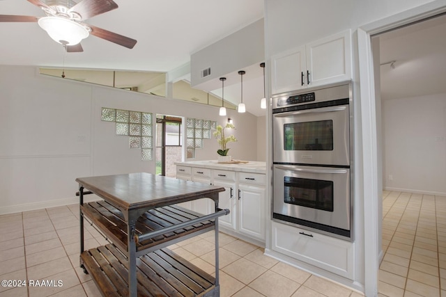 kitchen with white cabinets, light tile patterned flooring, decorative light fixtures, vaulted ceiling, and stainless steel double oven