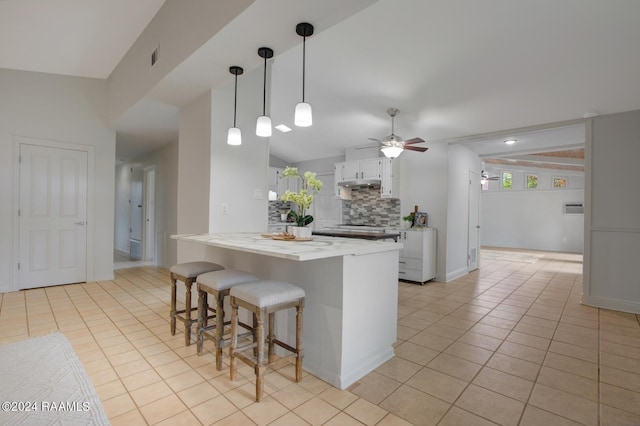 kitchen featuring pendant lighting, white cabinets, decorative backsplash, light tile patterned floors, and light stone counters