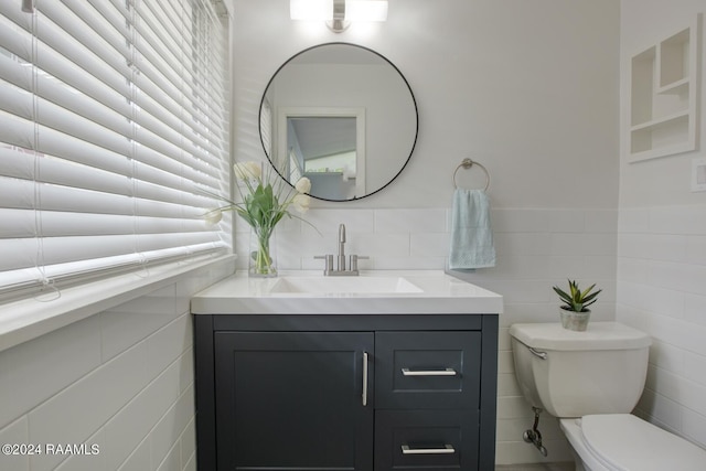 bathroom with vanity, tile walls, and toilet