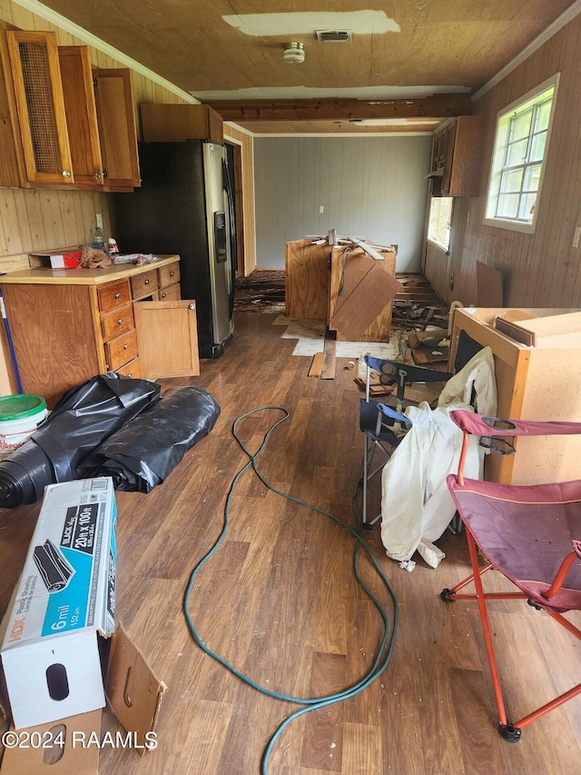 kitchen with stainless steel fridge, wood-type flooring, and wood walls